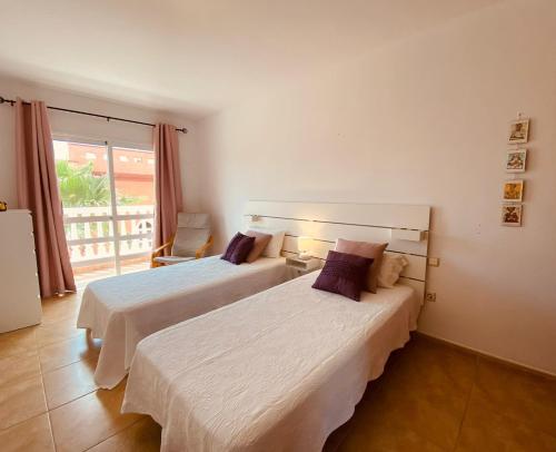 two beds in a hotel room with a balcony at Holiday for you Callao in Callao Salvaje