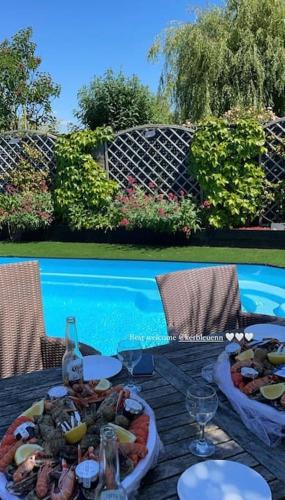une table avec deux assiettes de nourriture à côté d'une piscine dans l'établissement VILLA KER BLEUENN * 10 PERSONNES * PISCINE * SAUNA, à La Fresnais