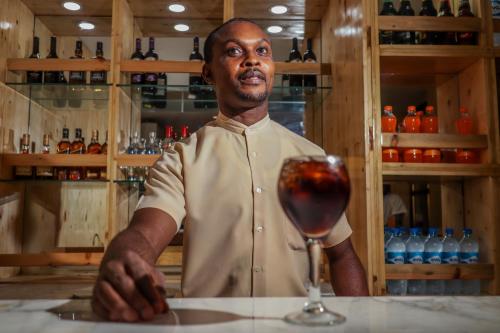 a man standing behind a counter with a glass of wine at De Rembrandt Classic Hotel in Ikeja