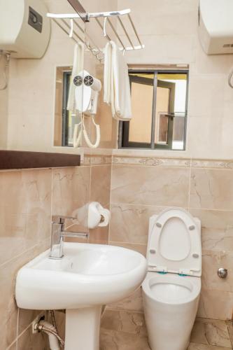 a bathroom with a toilet and a sink and a mirror at De Rembrandt Classic Hotel in Ikeja