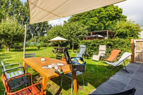 a picnic table with chairs and an umbrella in a yard at Vakantiehuis Wandelen en fietsen in de Kalkense Meersen dichtbij Gent in Laarne