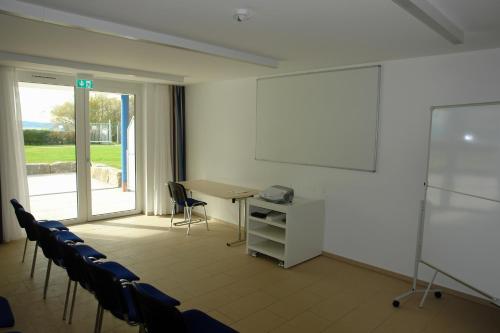 a meeting room with a table and chairs and a screen at CAP Rotach in Friedrichshafen