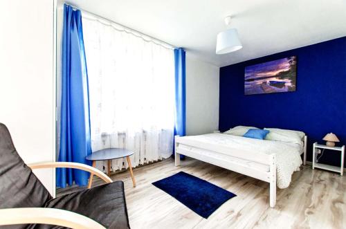 a bedroom with a bed and a blue wall at Dom Korsarza in Mikołajki