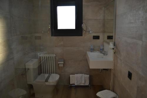 a bathroom with a toilet a sink and a mirror at Hotel Gran Sol in Solsona