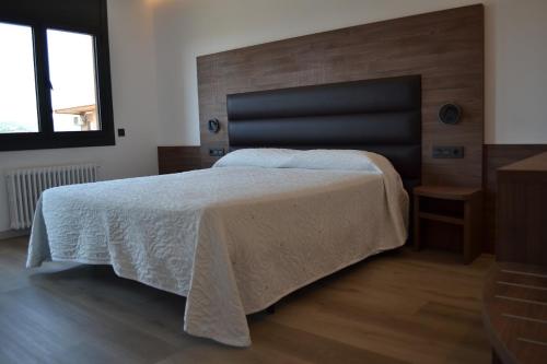 a bedroom with a large bed with a wooden headboard at Hotel Gran Sol in Solsona