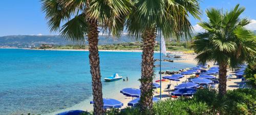a beach with chairs and umbrellas and the ocean at Residence La Torretta Briatico - Tropea in Briatico