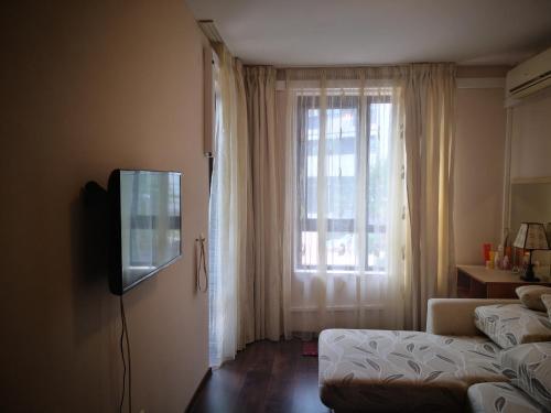 uma sala de estar com televisão e janela em Apart Complex Amphora Palace em Golden Sands