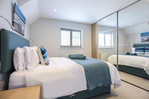 um quarto com 2 camas e um espelho grande em Seascape - 4 bed home in Bracklesham Bay em Chichester