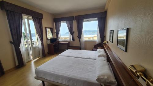 1 dormitorio con 1 cama grande en una habitación con ventanas en Hotel Las Sirenas en Viveiro