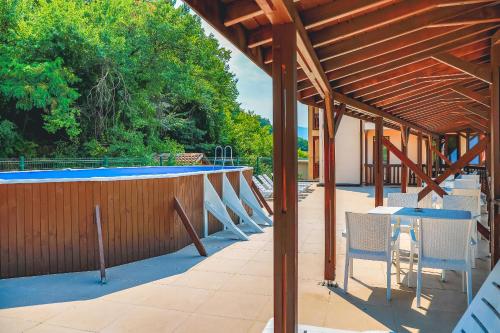 a patio with a table and chairs and a swimming pool at Стаи за гост Хит Хаус и СПА in Bratsigovo