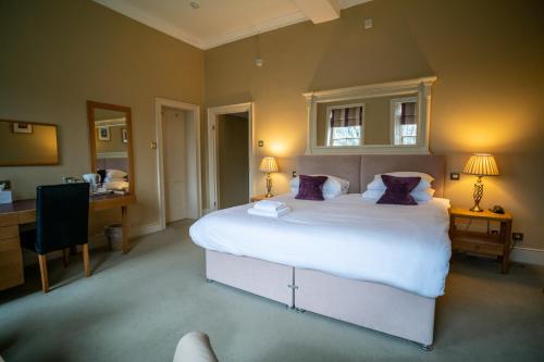 a bedroom with a large white bed with purple pillows at The Old Deanery - Restaurant With Rooms in Ripon