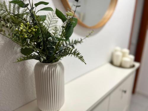 un jarrón blanco con flores en un mostrador en Apartamento Sant Roc, en Benidorm