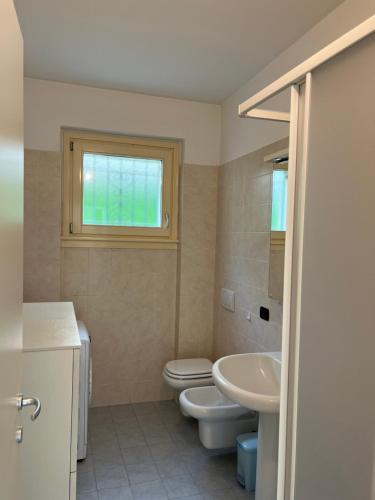 een badkamer met een wastafel en een toilet en een raam bij Lago e Giardino apartment in Bellagio