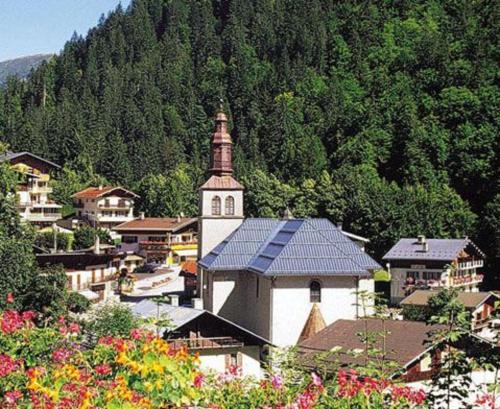 a small town with a church and a mountain at Hôtel Flor'Alpes in La Giettaz