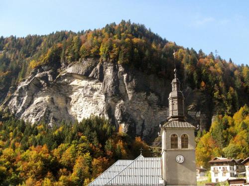 a building with a clock tower in front of a mountain at Hôtel Flor'Alpes in La Giettaz