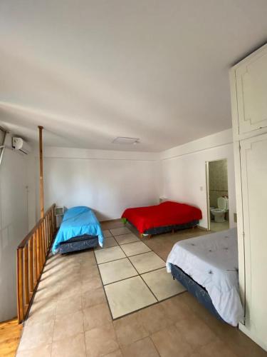 a bedroom with two beds and a red and blue blanket at Roosevelt in Buenos Aires