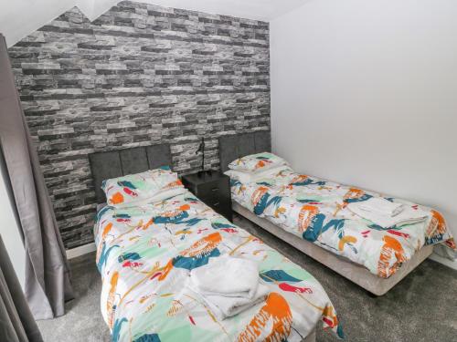 a bedroom with two beds and a brick wall at Dwyros in Pwllheli