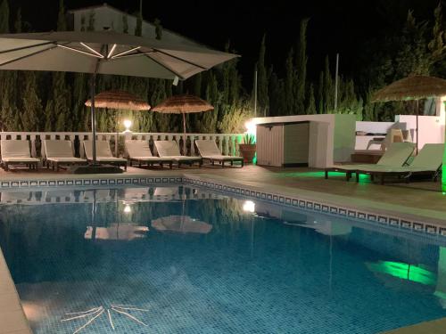 een zwembad met stoelen en parasols in de nacht bij Quinta Las Galgas in Calpe