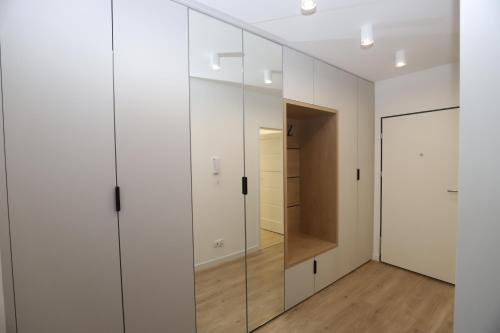 a dressing room with white cabinets and a mirror at Nowy w centrum in Giżycko