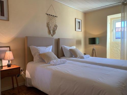a bedroom with two beds with white sheets and a window at Villa Candoso in Candoso