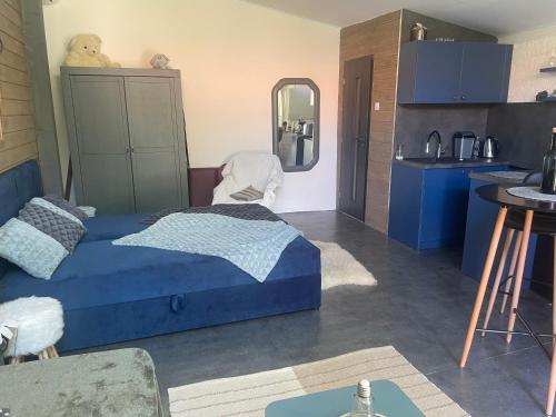 a bedroom with a blue bed and a kitchen at MonPe apartmánik s atmosférou in Komárno