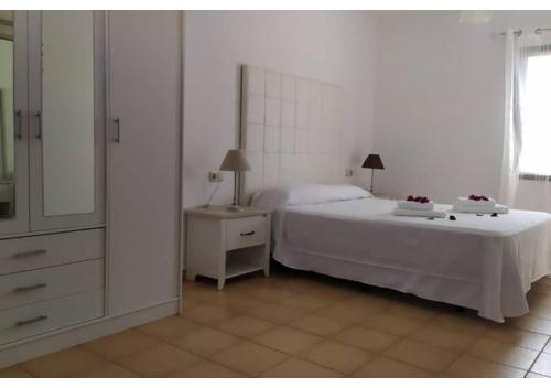 a bedroom with a bed and a dresser with a mirror at Anahi Homes Corralejo- Dracaena 18 in La Oliva