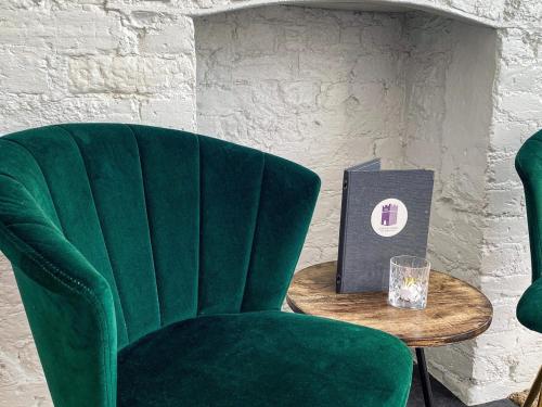 a green chair sitting next to a table with a book at Castle Hotel in Eynsford