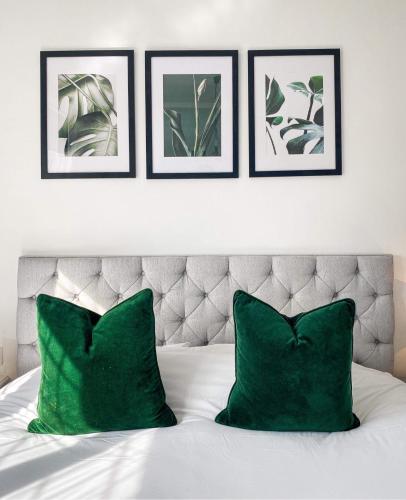 a white bed with green pillows and three framed pictures at Castle Hotel in Eynsford