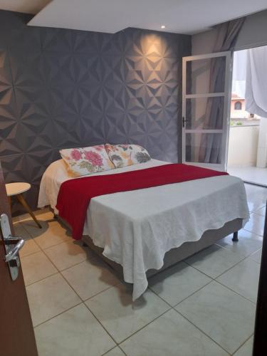 a bedroom with a bed with a red and white blanket at LUZ DO LUAR in Pedra Azul