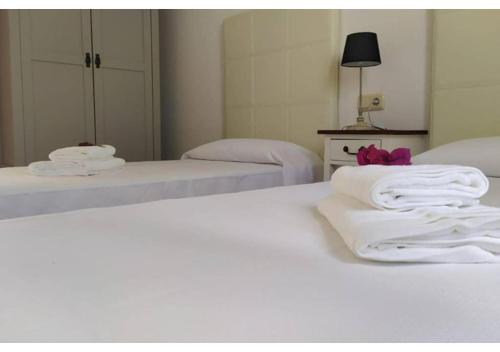 een slaapkamer met 2 bedden met witte lakens en handdoeken bij Anahi Homes Corralejo- Bicacarera 9 in La Oliva