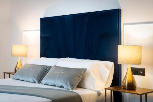 a bed with a blue headboard and two lamps at Apartamentos Casa del Arco de 2 a 6 personas in Andújar