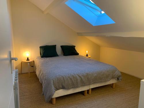 - une chambre avec un lit doté d'oreillers verts et une lucarne dans l'établissement Biby BeachHouse, à Lacanau