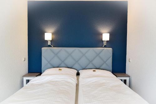 ein Schlafzimmer mit 2 Betten und einer blauen Wand in der Unterkunft Strandhochhaus SHC2 in Cuxhaven