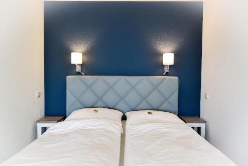 a bedroom with two beds and a blue wall at Strandhochhaus SHC2 in Cuxhaven