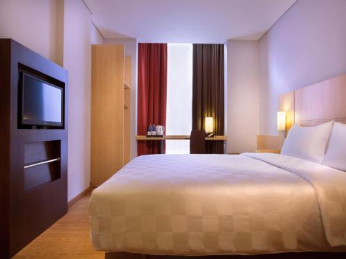 a hotel room with a bed and a flat screen tv at Ibis Jakarta Senen in Jakarta