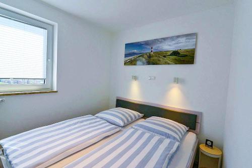 a bedroom with a bed with two striped pillows at Strandhochhaus SD09 in Cuxhaven