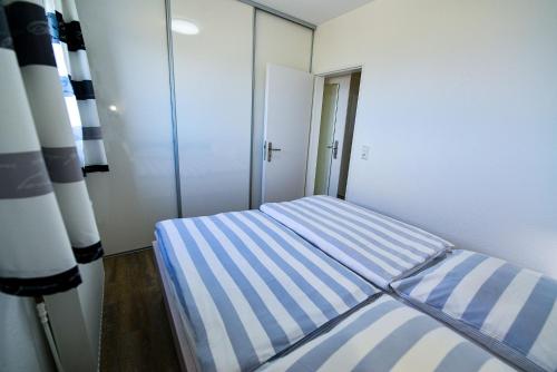 een kleine slaapkamer met een gestreept bed erin bij Strandhochhaus SF11 in Cuxhaven