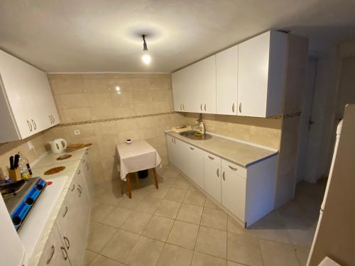 une petite cuisine avec des placards blancs et une table dans l'établissement Guest house Ruzica, à Sutomore