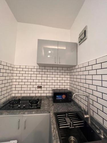 a kitchen with a stove and a white tiled wall at Luxury Studio Flat With Pool at Kingsland Lekki in Igboefon