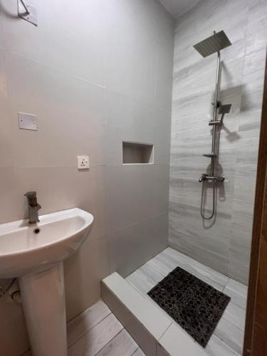 a white bathroom with a sink and a shower at Luxury Studio Flat With Pool at Kingsland Lekki in Igboefon