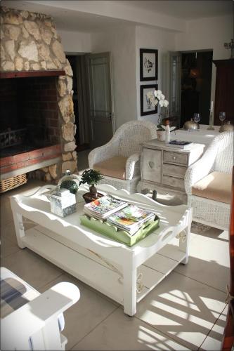 a living room with a white coffee table and a fireplace at Klokkiebosch Guesthouse in Jacobs Bay