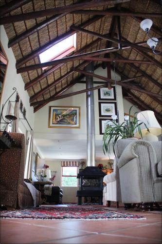 a living room with couches and a ceiling with beams at Klokkiebosch Guesthouse in Jacobs Bay