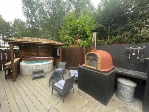 a patio with a hot tub and a grill and a hot tub at Woodpecker Log Cabin with hot tub, pizza oven bbq entertainment area, lakeside with private fishing peg situated at Tattershall Lakes in Tattershall
