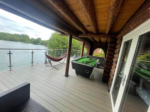 a deck with a hammock and a pool table at Woodpecker Log Cabin with hot tub, pizza oven bbq entertainment area, lakeside with private fishing peg situated at Tattershall Lakes in Tattershall