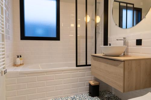 a white bathroom with a tub and a sink at La Maison des Embruns in Plouarzel