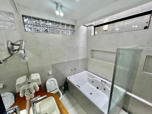 Un baño con bañera, inodoro y lavabo. en Cabana Toscana, en Campos do Jordão