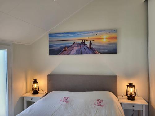 ein Schlafzimmer mit einem Bett mit zwei Nachttischen und einem Gemälde an der Wand in der Unterkunft Luxe vrijstaande chalet voor gezinnen en stellen in Elahuizen