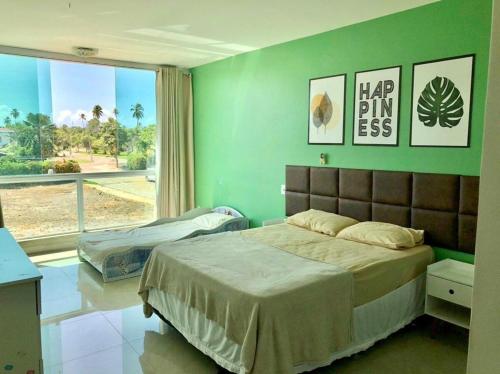 una camera da letto con un letto e una parete verde di Casa Grande Angra de Ipioca Hibiscus a Paripueira