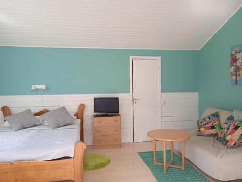 a bedroom with a bed and a table and a couch at Talluddens Stugby in Färjestaden