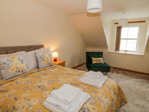 a bedroom with a bed with towels on it at Bumblebee Cottage in Stranraer